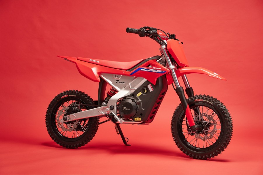 A red-white-and-blue 2022 Honda CRF-E2 electric dirt bike on its kick-stand