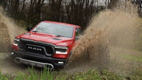 Red pickup truck driving through a swamp, fishtails of water erupting from each wheel well.