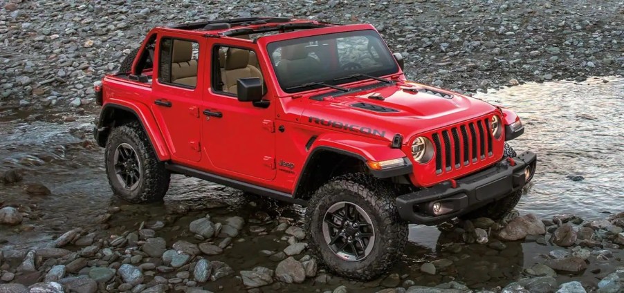 A red 2022 Jeep Wrangler 4x4 parked next to a lake.