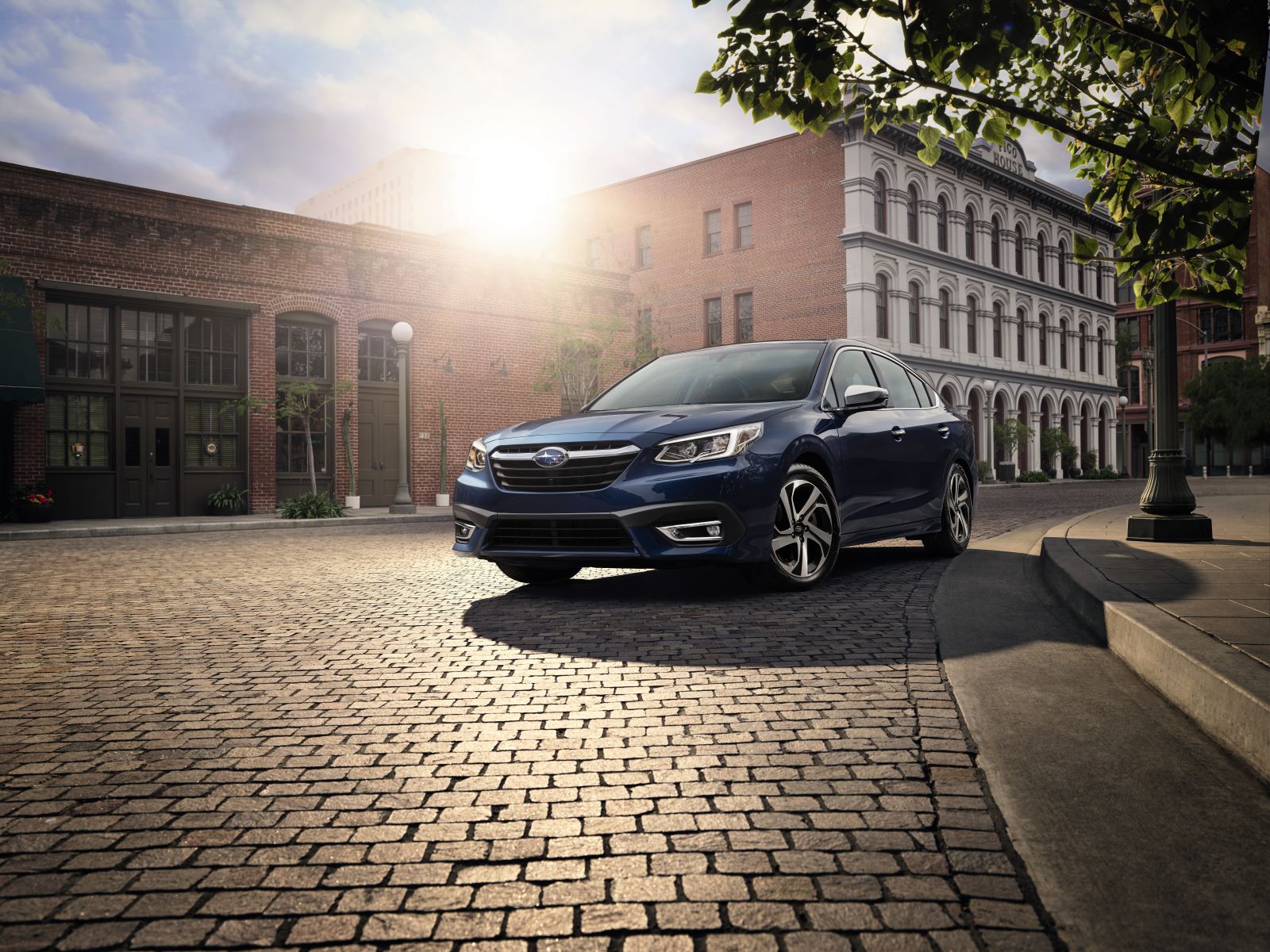 Front angle view of the 2022 Subaru Legacy in dark blue, shown driving on a cobblestone street in a city 