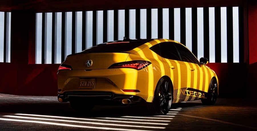 The rear 3/4 view of the yellow 2023 Acura Integra Prototype in a garage