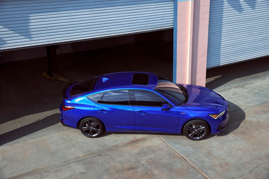 Blue 2023 Acura Integra liftback sports car parked directly outside of a high-end garage