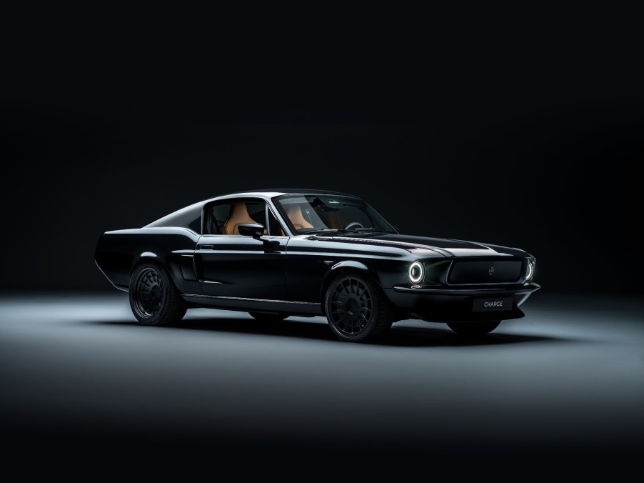 A profile view of Charge Cars new electric Mustang. The car is black and parked in a black studio background.