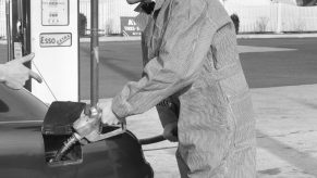 gas station attendant fills up gas tank in black and white