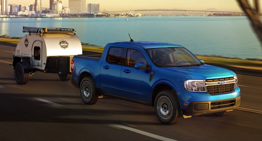 A blue 2022 Ford Maverick midsize pickup truck is towing a small trailer.