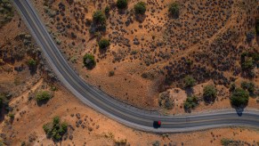 Drone aerial view of winding road and red car in Utah.