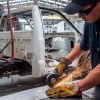 Mexican factory worker cuts a piece of metal while assembling a heavy-duty truck.