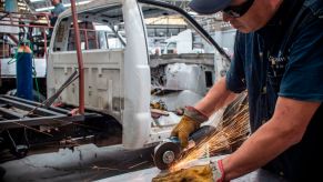 Mexican factory worker cuts a piece of metal while assembling a heavy-duty truck.