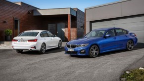 Two certified pre-owned 2019 BMW 3 Series sedans by a garage