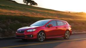 Lithium Red Pearl 2022 Subaru Impreza Hatchback driving by a hill