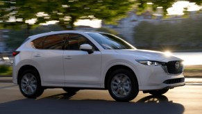 A white 2022 Mazda CX-5 small SUV is driving on the road.