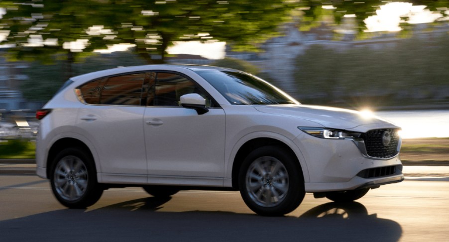 A white 2022 Mazda CX-5 small SUV is driving on the road.