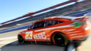 Red NASCAR Next Gen car moving fast down a track.