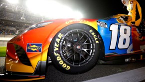 Closeup of a driver sliding into a NASCAR Next Gen car with the driver sliding into the cabin in the background.