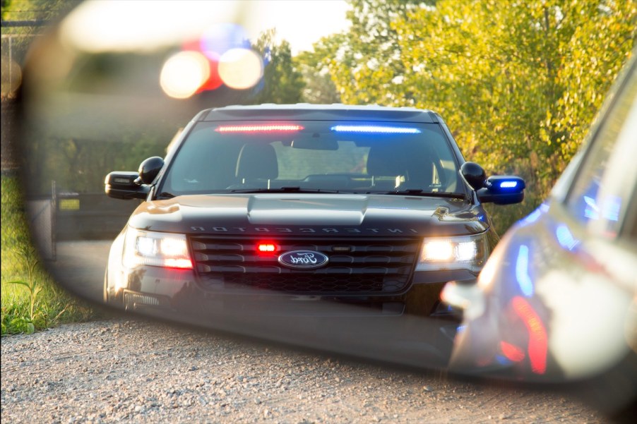 Ford interceptor SUV framed in a vehicle's rearview mirror during a traffics top.