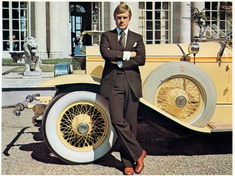 Robert Redford playing Jay Gatsby, leaning against a 1928 Roll-Royce car.