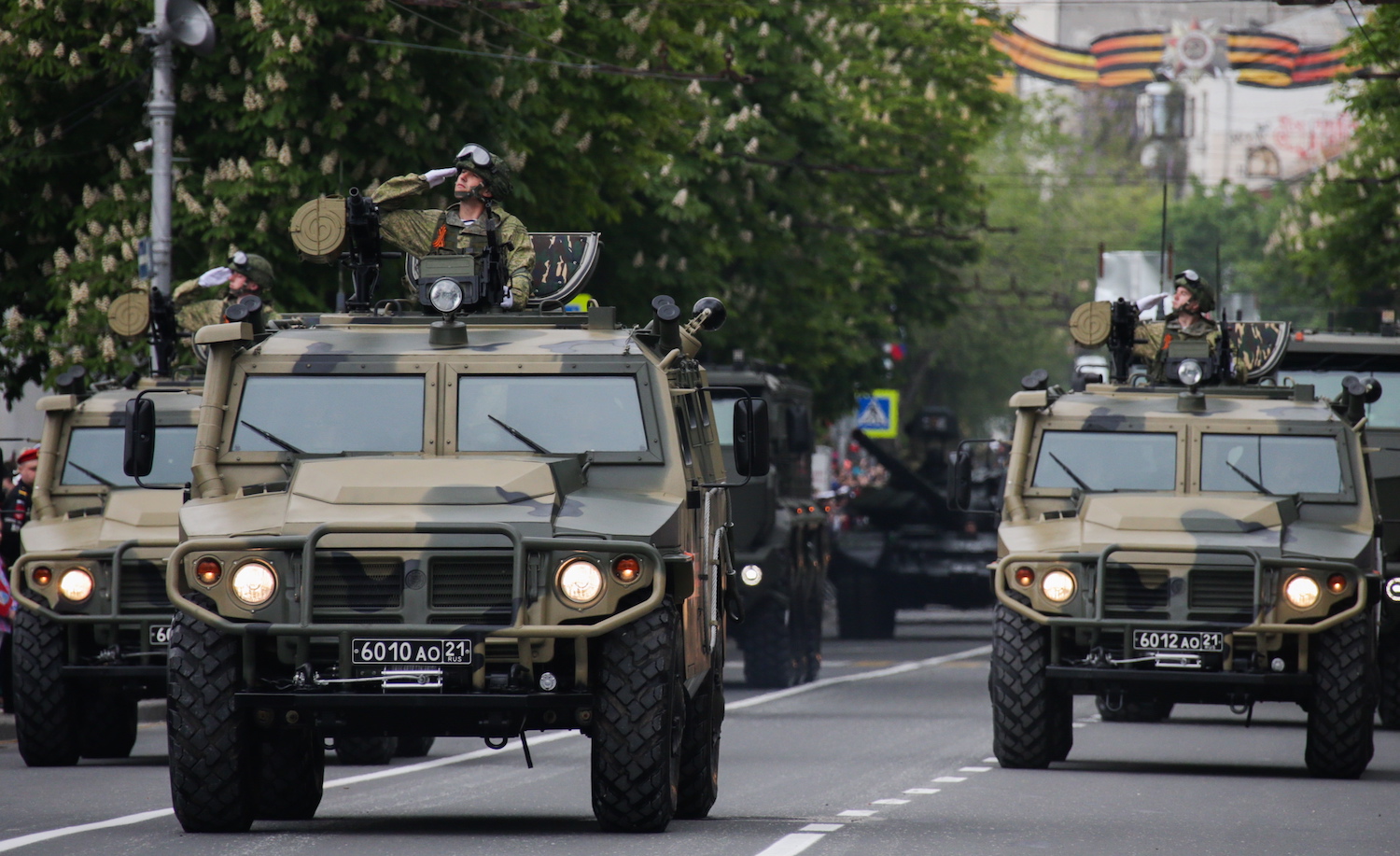 Cummins-powered Russian military vehicles parade through the streets of Crimea while a soldier salutes from the roof of each.