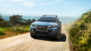 A light blue 2022 Hyundai Santa Cruz driving down a dirt road.