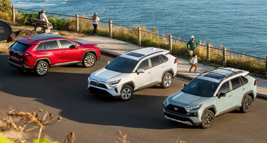 A red, white , and blue Toyota RAV4 parked in a parking lot near the water.