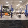 Two Ford F-150s in a garage being undercoated with rustproof corrosion resistant spray.