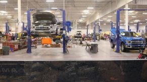 Two Ford F-150s in a garage being undercoated with rustproof corrosion resistant spray.