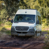 White 2023 Mercedes-Benz Sprinter Passenger Van driving off-road, highlighting its release date and price