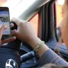 A woman texting and browing Twitter on her smartphone while driving a motor vehicle