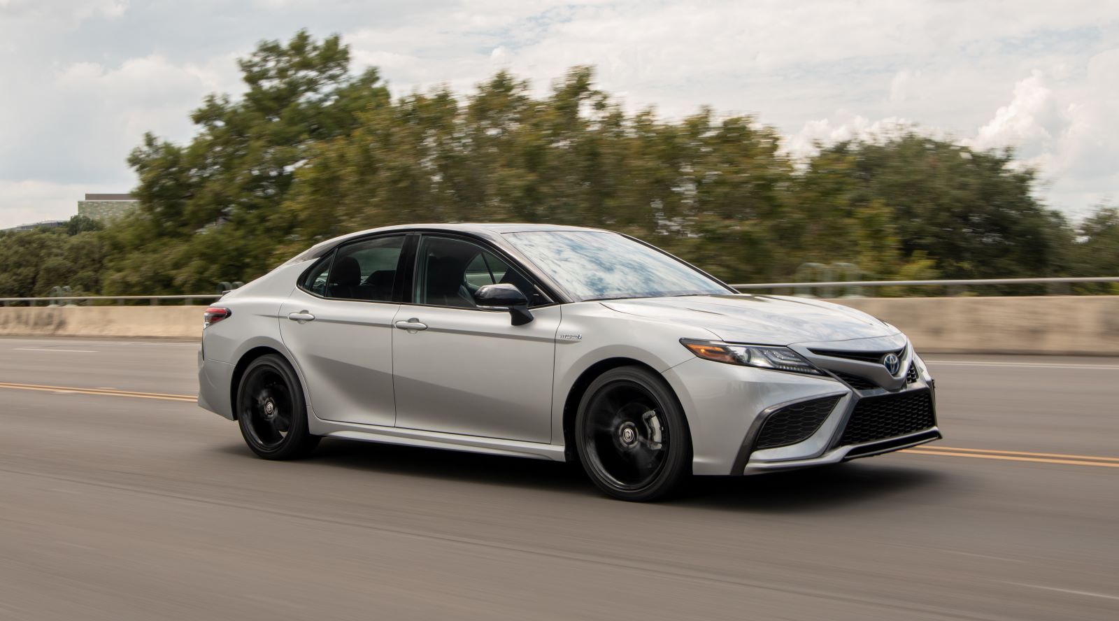 Action shot of a silver 2022 Toyota Camry Hybrid sedan driving