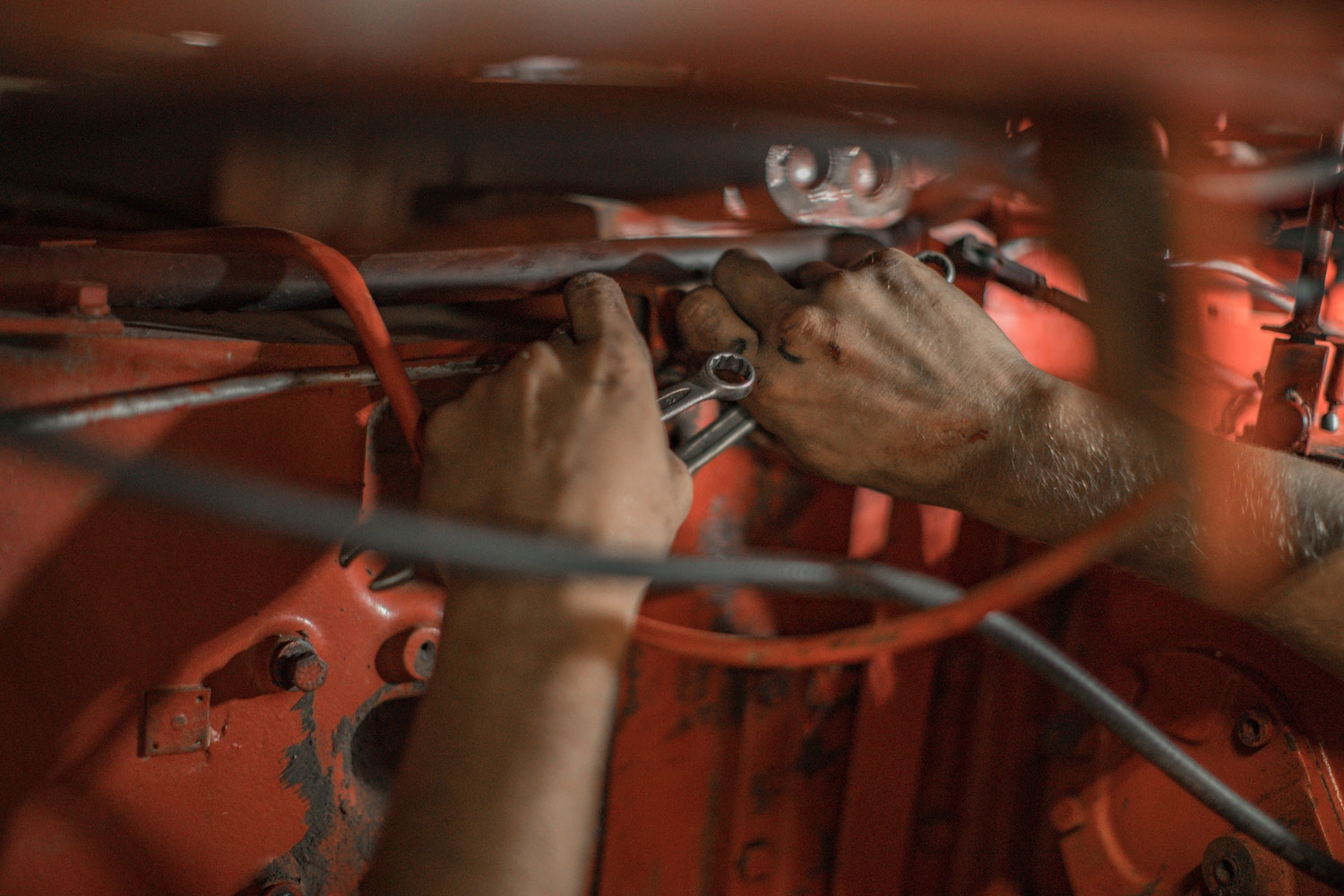 Detail shot of the hands of a mechanic holding wrenches to fix a classic car.