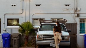 Young diesel enthusiast and her white Chevy truck parked by a building.