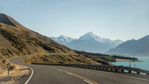 Beautiful highway running between a lake and mountain range.