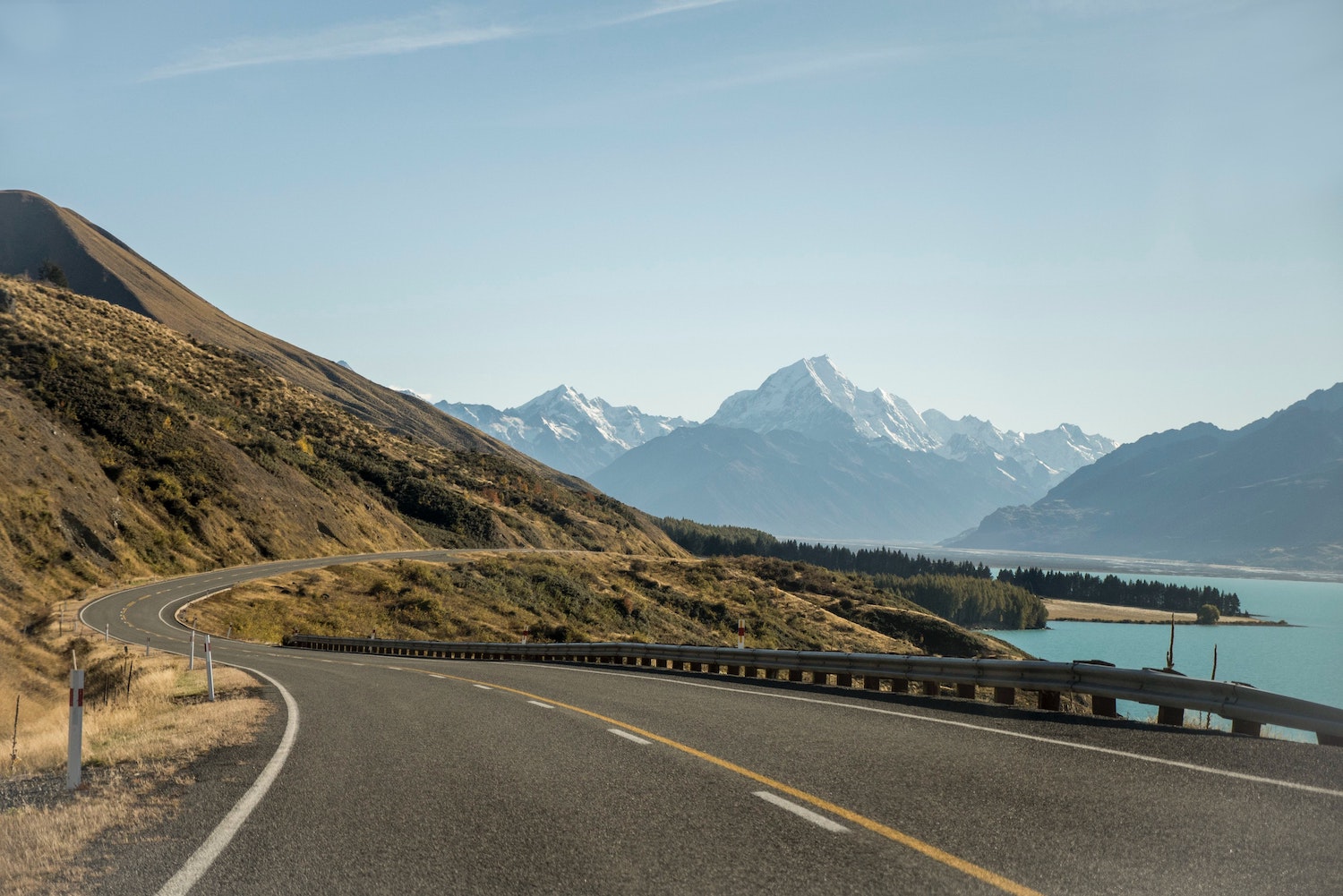 Beautiful highway running between a lake and mountain range.