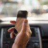 Man driving car and checking the smartphone in first person view.