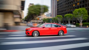 Moving shot of a red, 11th-generation 2022 Honda Civic driving in a city