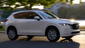 A white 2022 Mazda CX-5 small SUV is driving on the road.