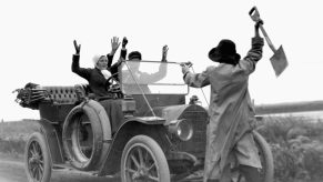 black and white photo of a man with a gun stealing a car