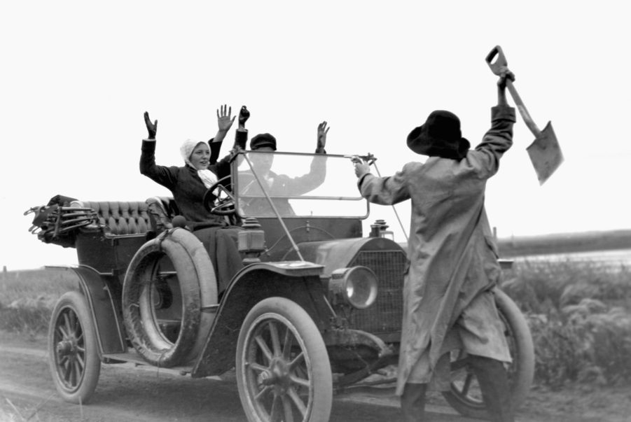 black and white photo of a man with a gun stealing a car