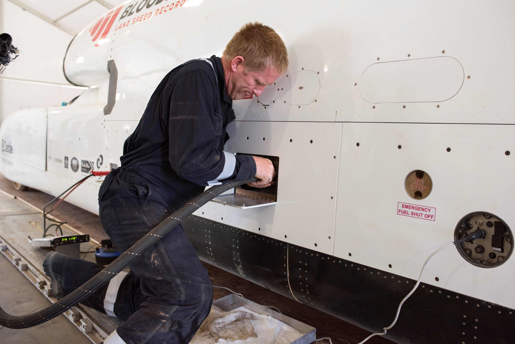 A flight technician plugging a hose into the jet-propelled British Bloodhound LSR car to refuel it