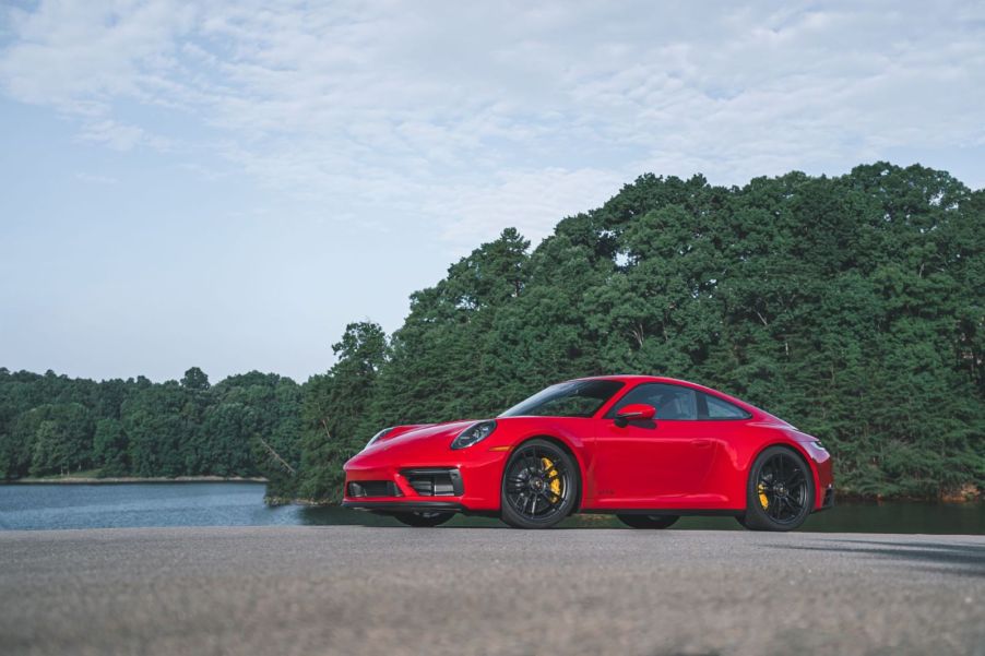 Bright red 2022 Porsche 911 GT3 sports car parked next to a lake