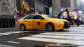 A NYC yellow cab driving in the city. Recently, Uber agreed to list taxis on its app