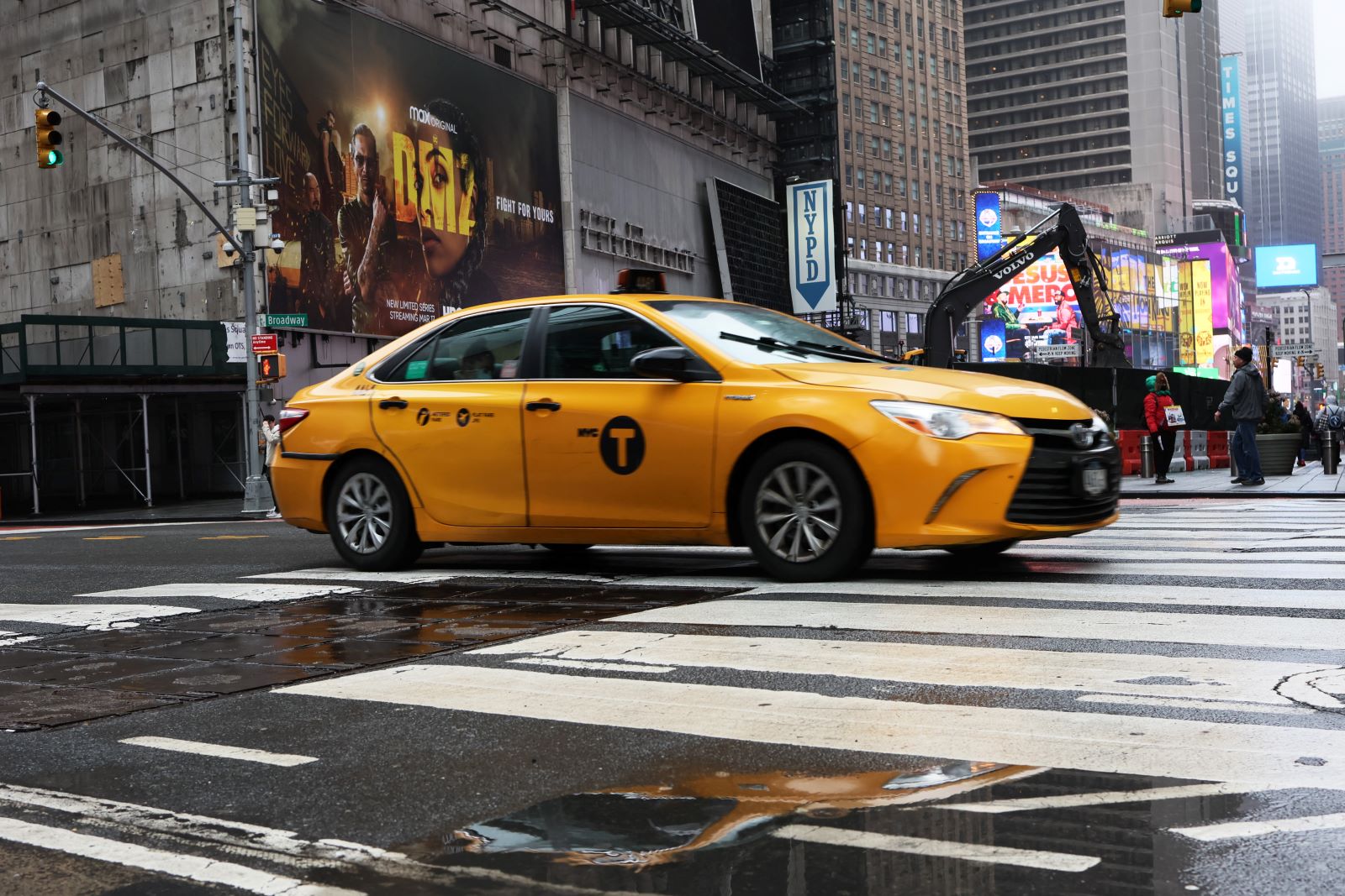 A NYC yellow cab driving in the city. Recently, Uber agreed to list taxis on its app