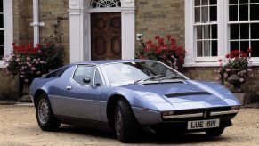 A blue 1980 Maserati Merak SS in front of a mansion