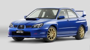 A blue 2006 Subaru Impreza WRX STI with gold wheels in a white studio