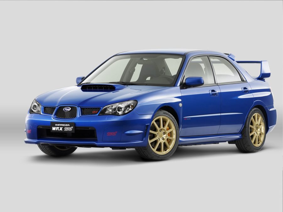 A blue 2006 Subaru Impreza WRX STI with gold wheels in a white studio