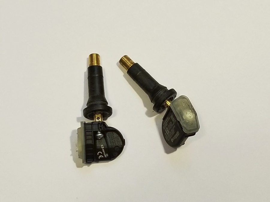 Two valve stem type 2013 Fiat 500 Abarth tire pressure sensors against a white background