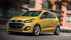 The 2022 Chevy Spark subcompact hatchback in yellow driving through an urban cityscape