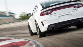 A white Dodge Charger Hellcat cornering on a racetrack.