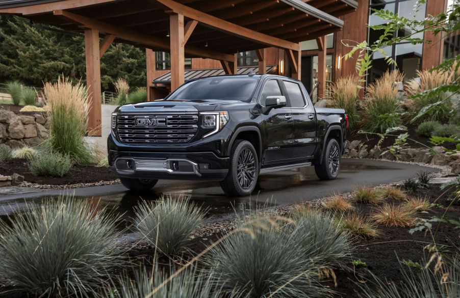 The 2022 GMC Sierra 1500 Denali Ultimate full-size premium pickup truck parked on the driveway plaza of a luxury forest home