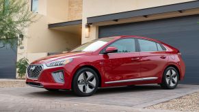 The 2022 Hyundai Ioniq Hybrid hatchback model in red parked outside of a home garage on a cobblestone driveway