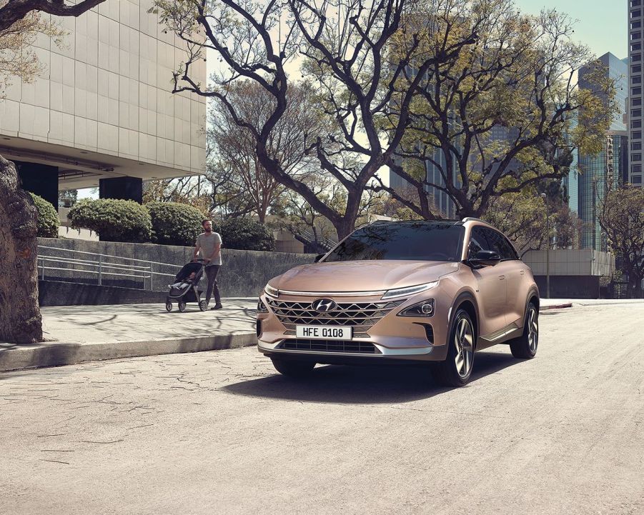 A gold color 2022 Hyundai Nexo sitting outside a building in a city environment.